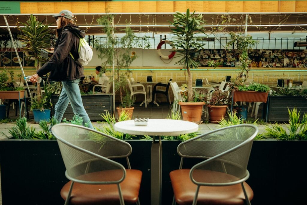Ambient view of an outdoor café with empty chairs and a passerby, capturing urban relaxation.