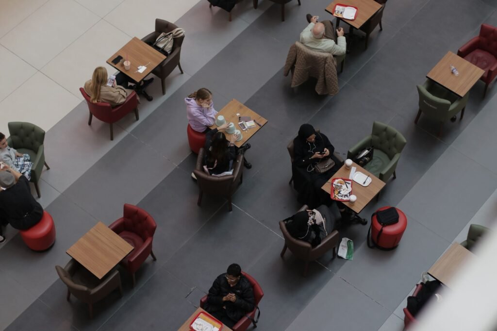 Aerial shot of people sitting in a cafeteria with tables and chairs, viewed from above.