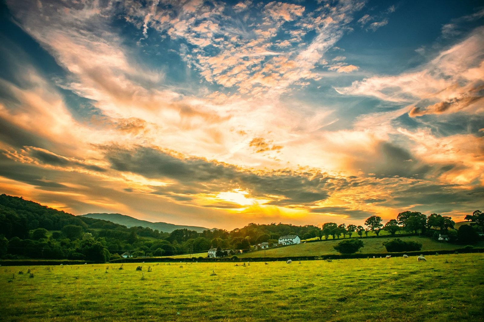 Beautiful countryside landscape with rolling hills and vibrant sky during sunset.