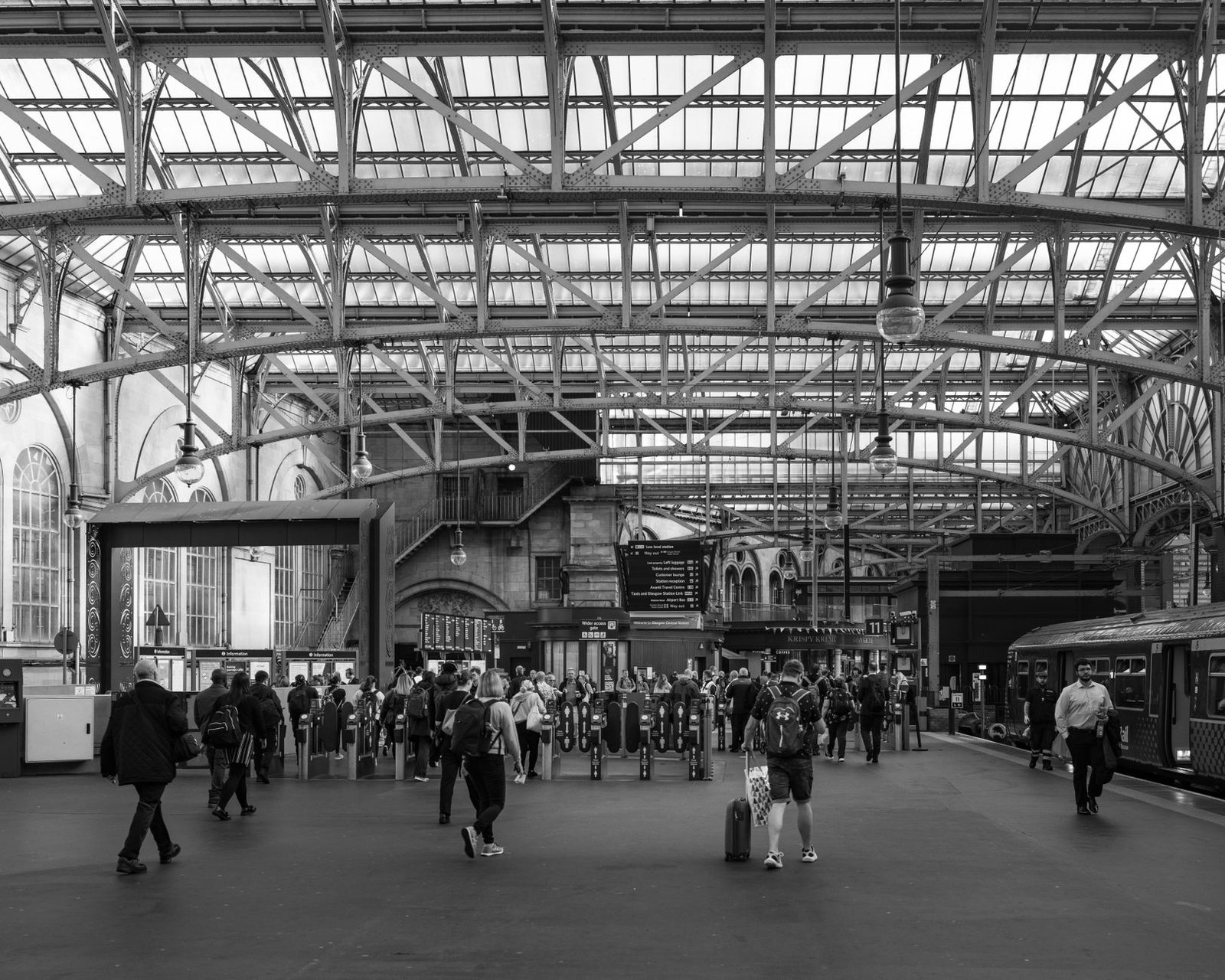 Black and white image of bustling Glasgow Central Station in Scotland, showcasing architectural details.