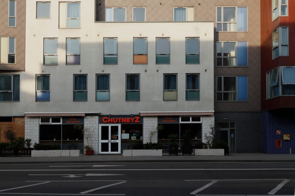Front view of a modern building featuring Chutneyz cafe on a city street.