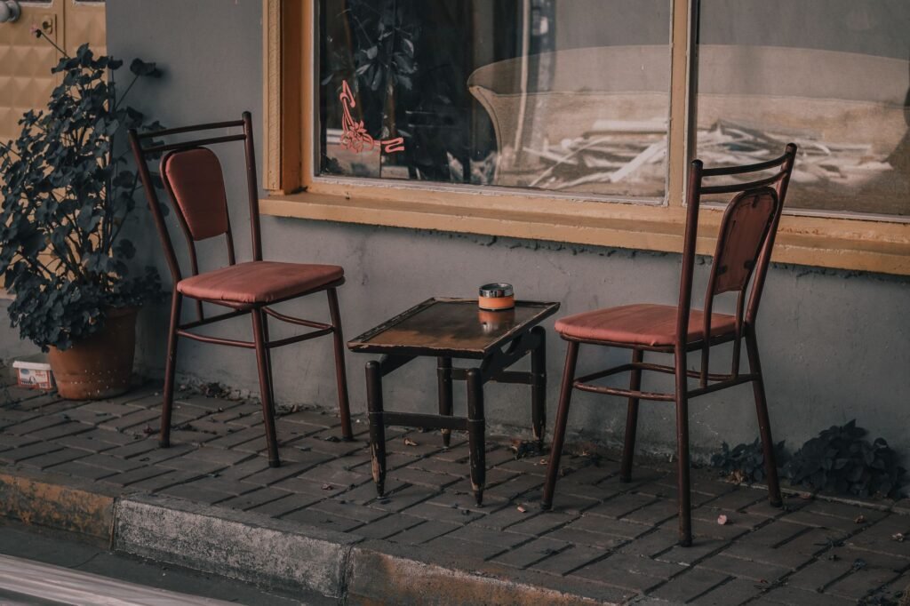 A quaint outdoor café setting with red chairs and table on a brick sidewalk.