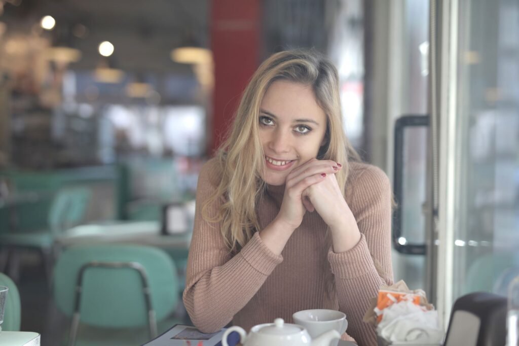 A cheerful woman in a cozy café, enjoying a relaxed moment with a smile.