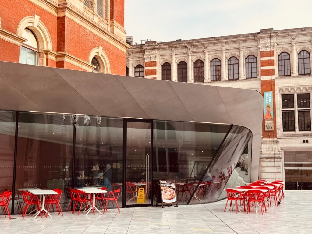 Contemporary cafe with red chairs set against a historic architectural backdrop, offering urban charm.