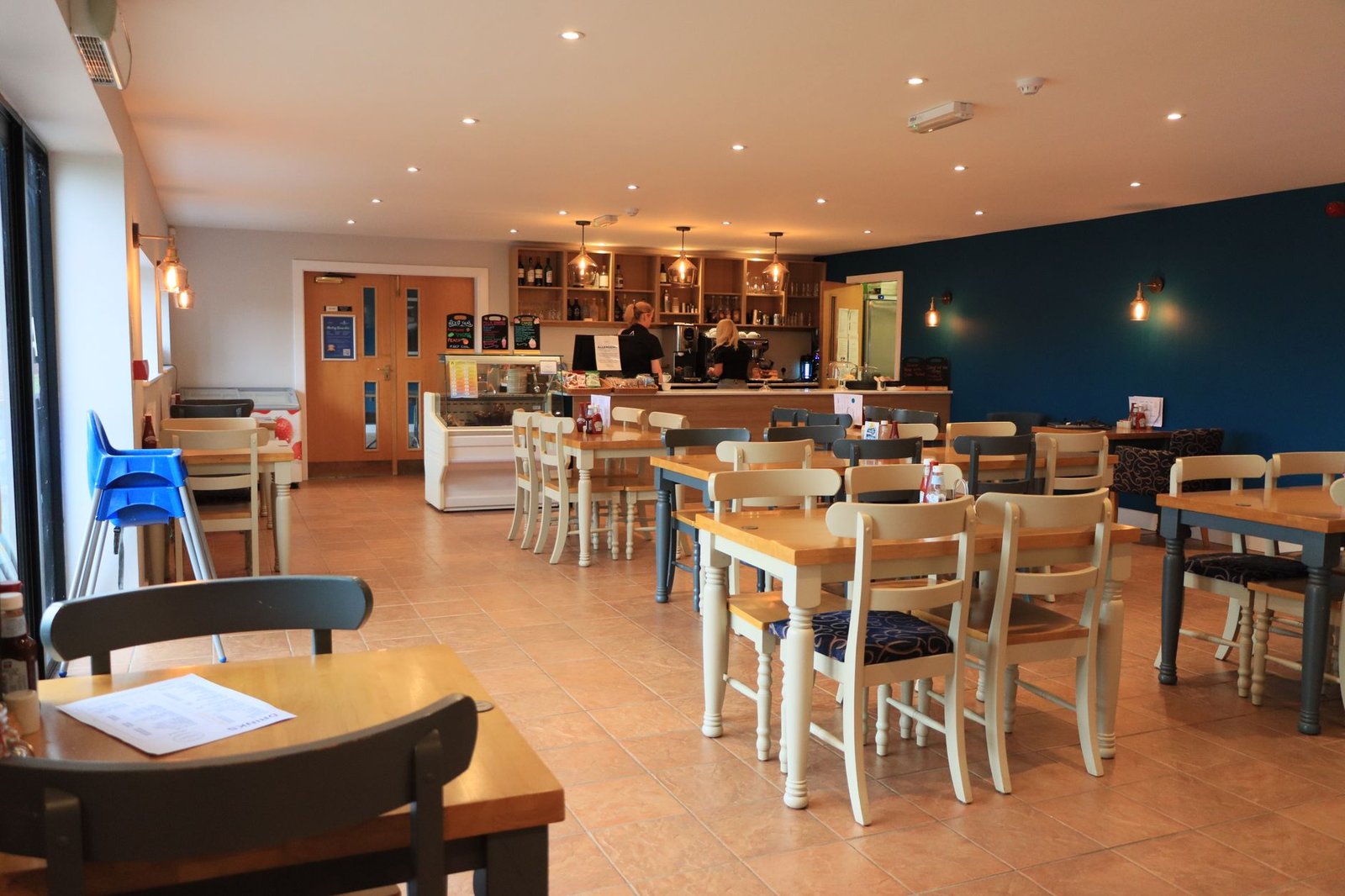 A cozy and modern café interior in England with wooden tables and bright lighting.