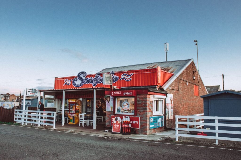 Exterior view of a quaint seaside cafe with rustic architecture and vibrant signage.