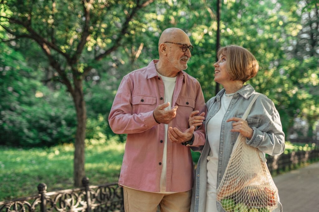 Senior couple walking together in a park enjoying a conversation on a sunny day.