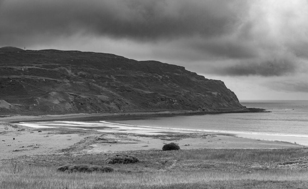 A stunning black and white capture of a rugged Scottish coastline under dramatic skies.