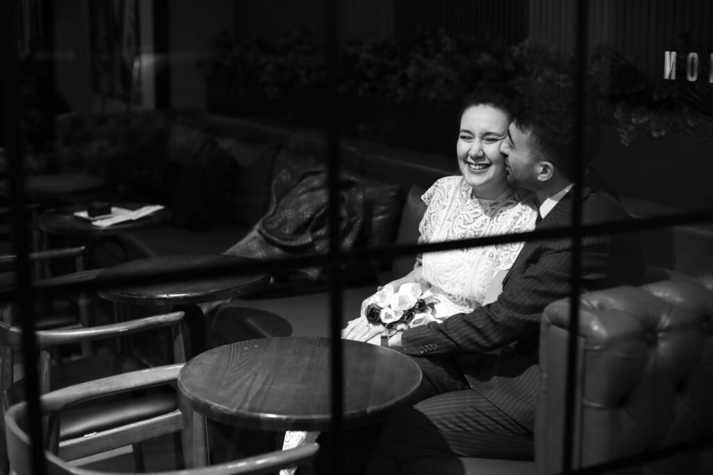 A couple sharing a joyous moment in a cozy coffee shop setting.