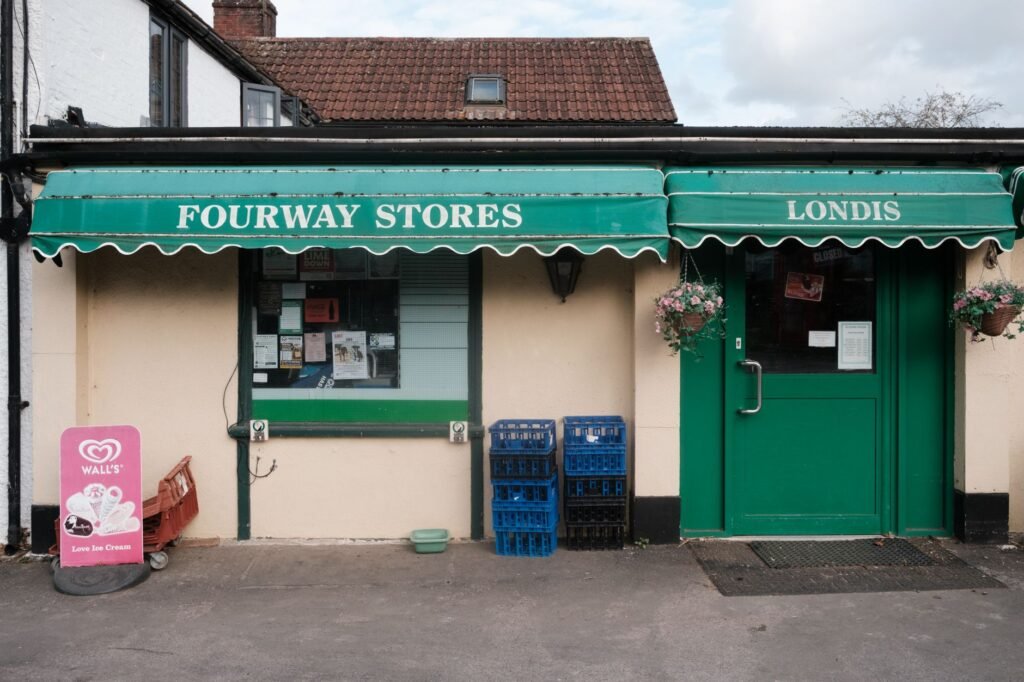 A classic small-town shopfront with green awnings and market signage.