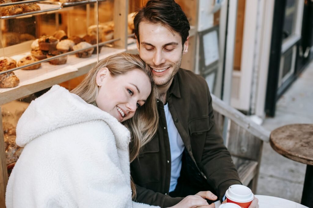 High angle of young happy couple relaxing in cosy bakery and drinking hot coffee