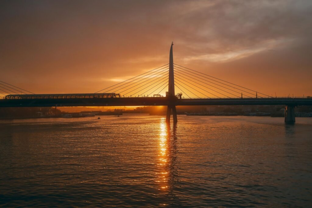 Stunning sunset view of a modern suspension bridge with warm reflections on a calm river.