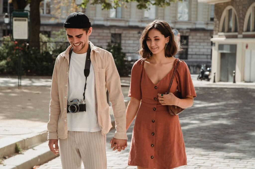 Smiling couple walking hand in hand outdoors, capturing a moment of love and happiness.