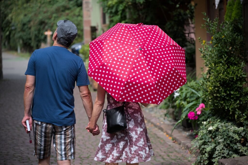 Couple holding hands under a polka dot umbrella in Kaysersberg, France.