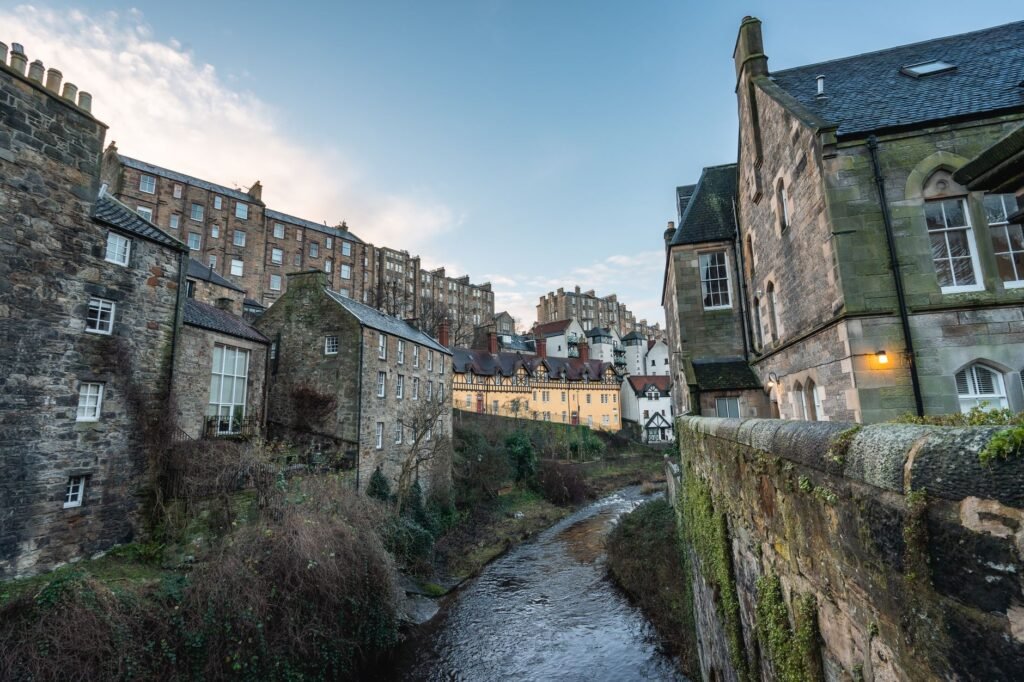 Charming view of Edinburgh's classic stone architecture by a peaceful river in Scotland.