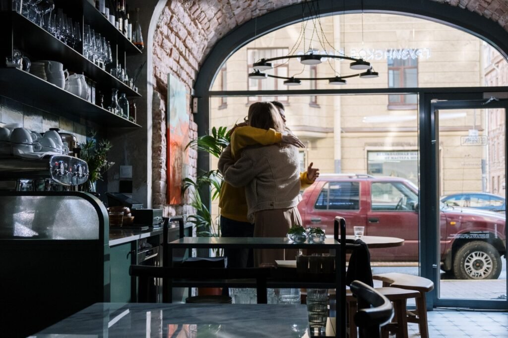 A couple embraces warmly inside a stylish café, capturing a moment of affection.