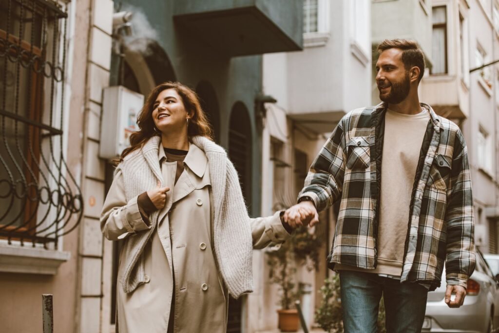 Happy couple holding hands while walking together down a picturesque city street.