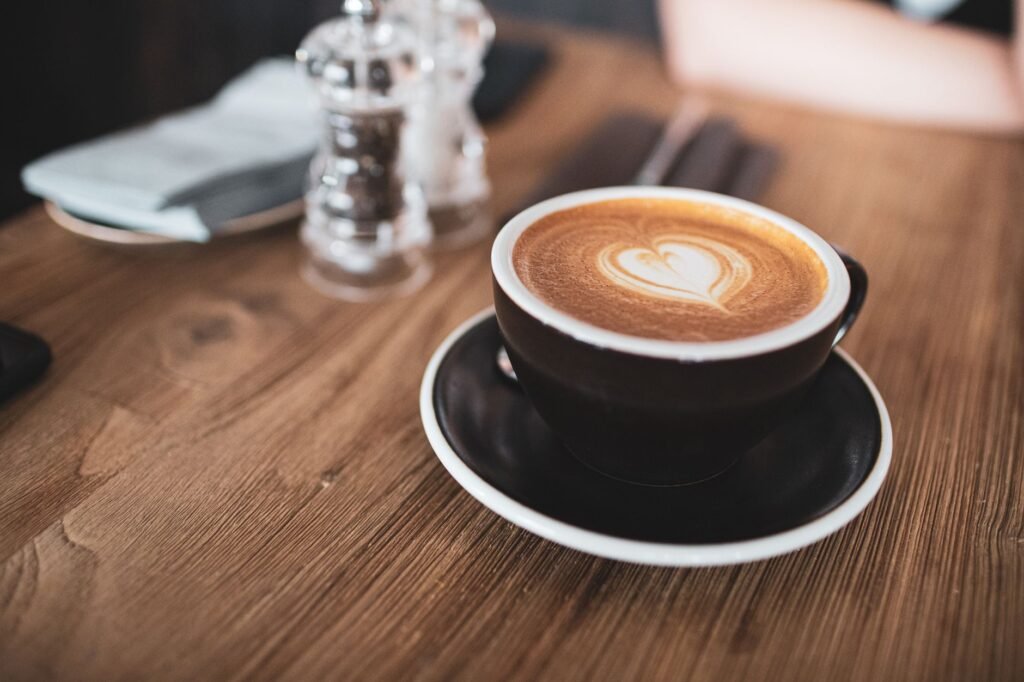 Warm latte with heart-shaped art in a cozy wooden cafe setting.
