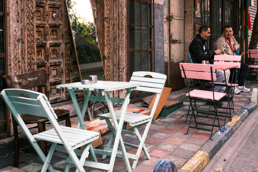 Quaint street café with colorful tables and chairs. Two men converse in the background.