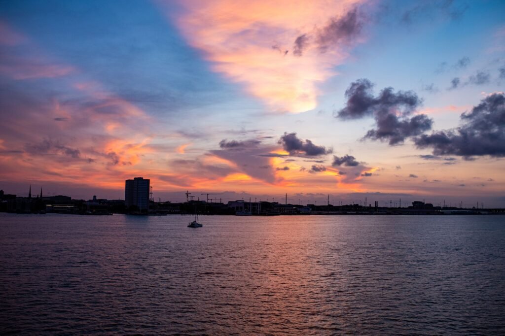 A stunning city skyline at sunset with vibrant colors reflecting on the water surface.