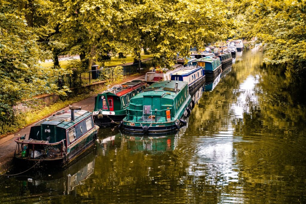 Charming canal boats moored in a lush London park, reflecting summer tranquility.