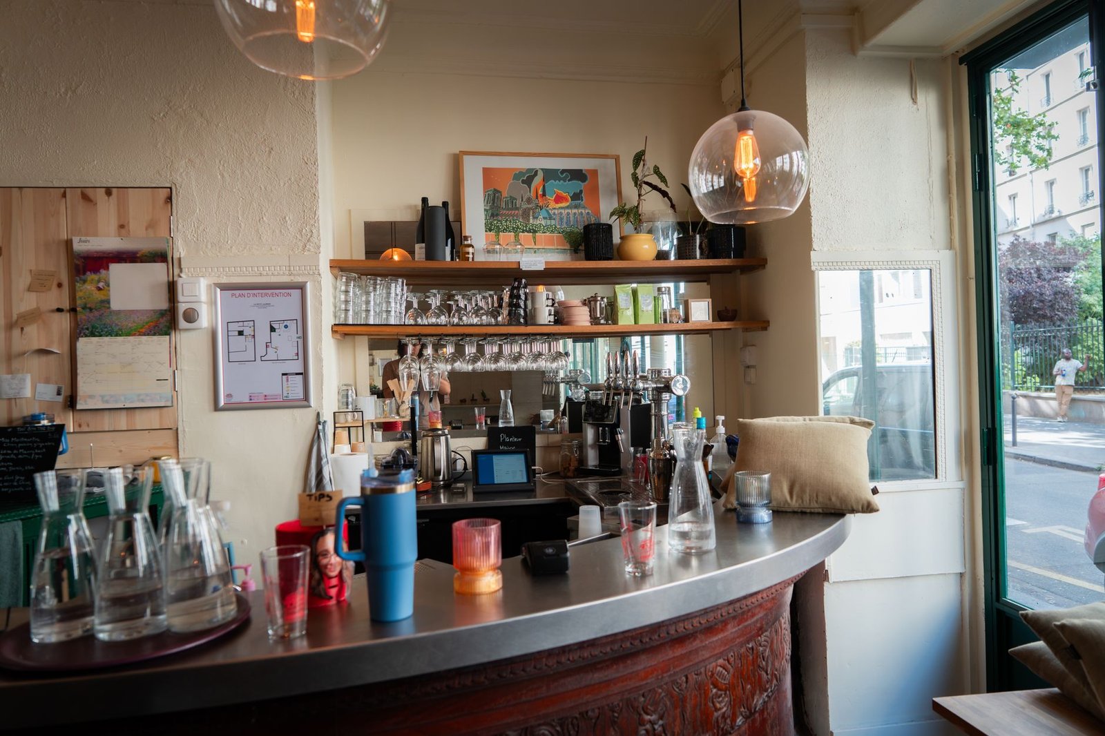 Charming cafe interior featuring a modern bar setup with hanging lights and glassware.