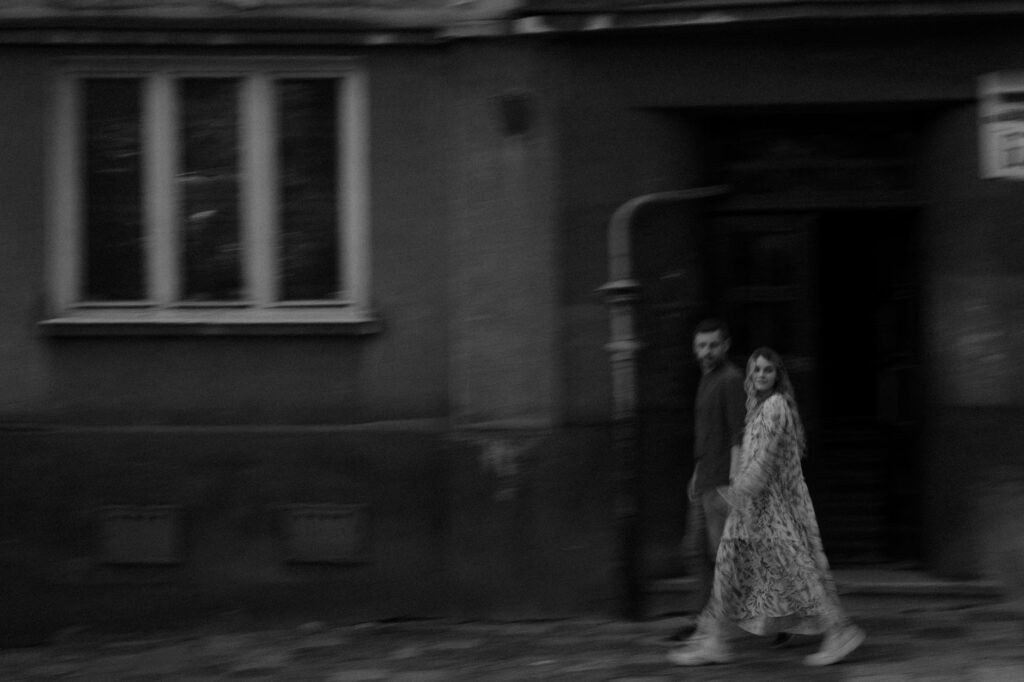 Blurred black and white image of couple walking together on a city street, creating a dreamy and artistic effect.