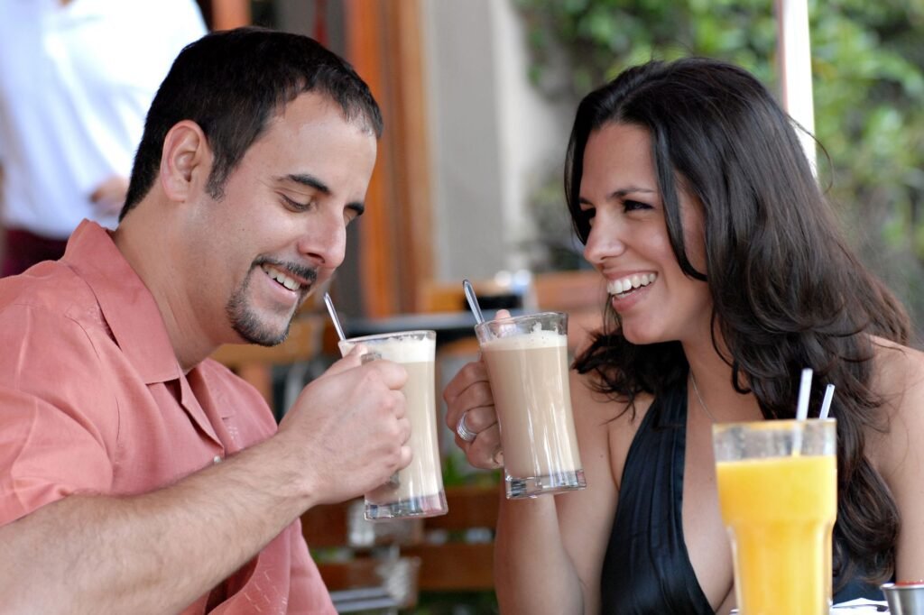 Happy couple is toasting with drinks at a Miami Beach cafe, enjoying a sunny day.