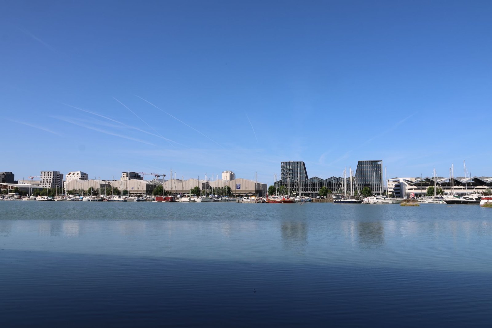 Scenic view of a modern urban harbor with boats and clear skies.
