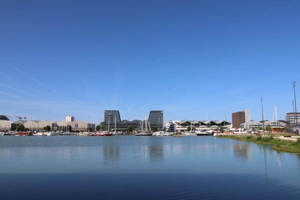 A vibrant cityscape featuring modern buildings and sailboats on a clear day.