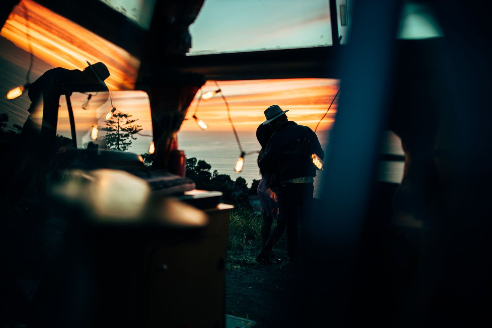 Romantic silhouette of a couple embracing at sunset with a scenic coastal backdrop.