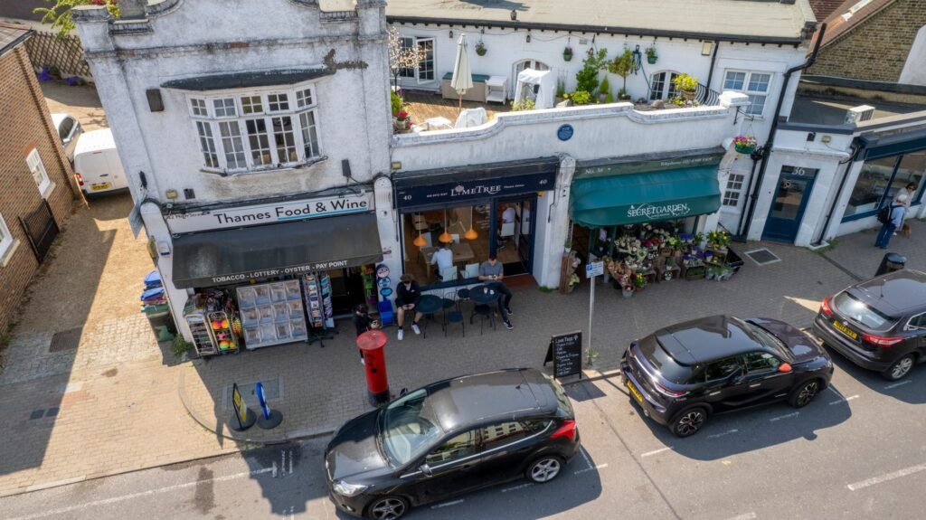 Aerial view of shops and pedestrians on a sunny street in Thames Ditton, England.