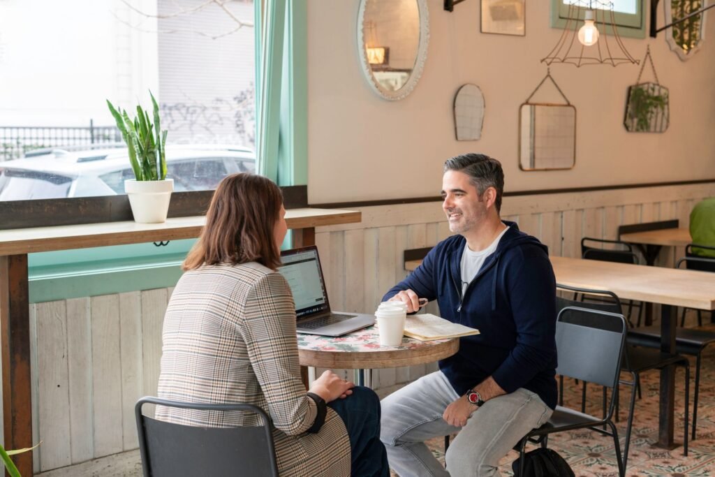 Two adults having a business discussion over coffee in a modern cafe setting.