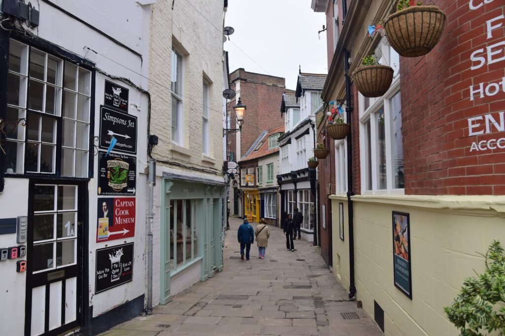Explore a quaint cobblestone alley in Whitby with historic architecture and charming shops.