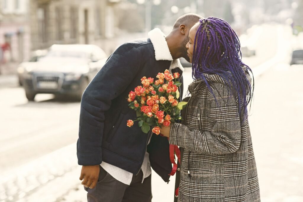 Couple on a city street sharing a romantic moment with flowers in winter.