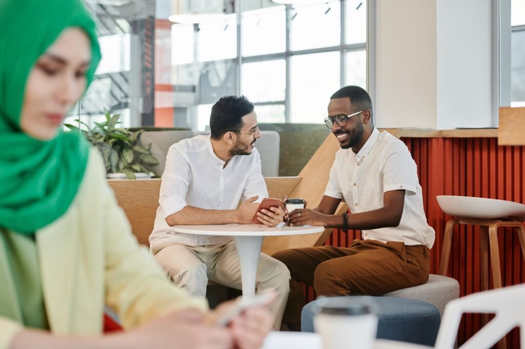 Two friends engage in lively conversation while enjoying coffee in a modern cafe setting.