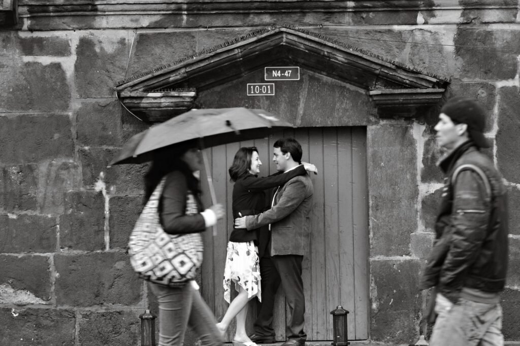 Black and white photo of a couple embracing against a rustic wall in Quito, Ecuador.