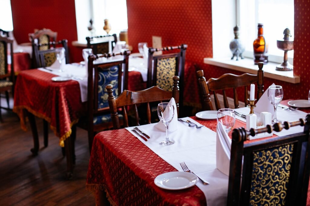 Lavishly set dining tables with elegant cutlery and rich decor in a classic restaurant setting.