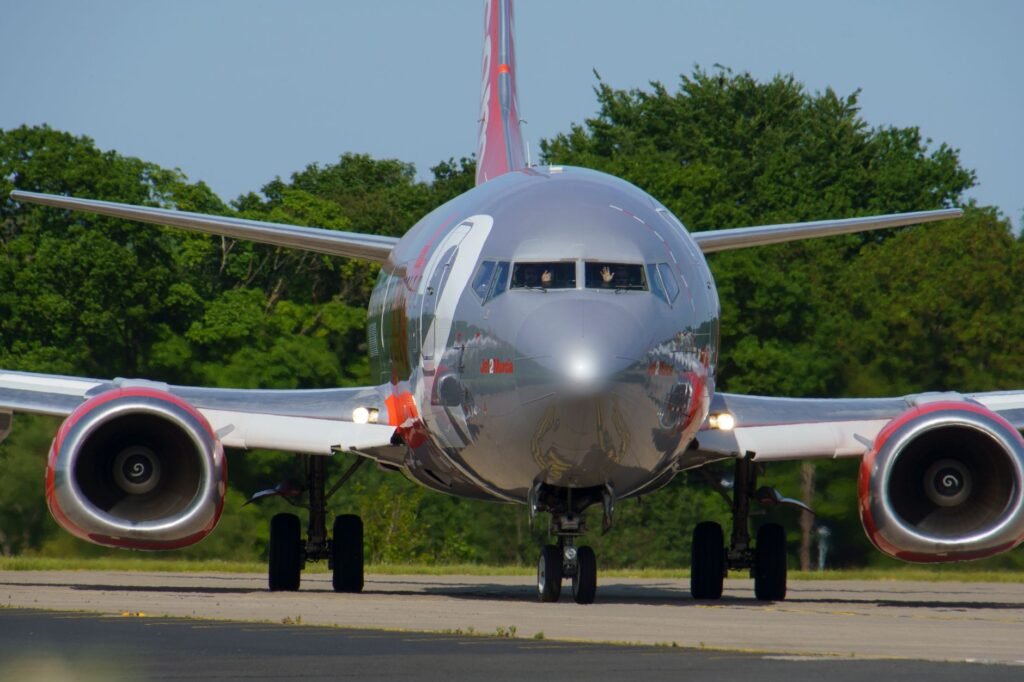 Front view of an airplane on runway in Yeadon, UK, surrounded by greenery.