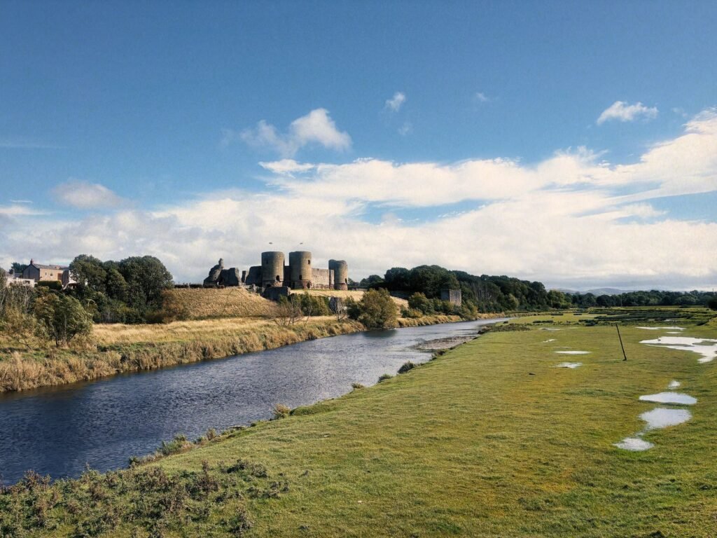 Scenic view of Rhuddlan Castle beside the Clwyd River in Wales under a clear blue sky.