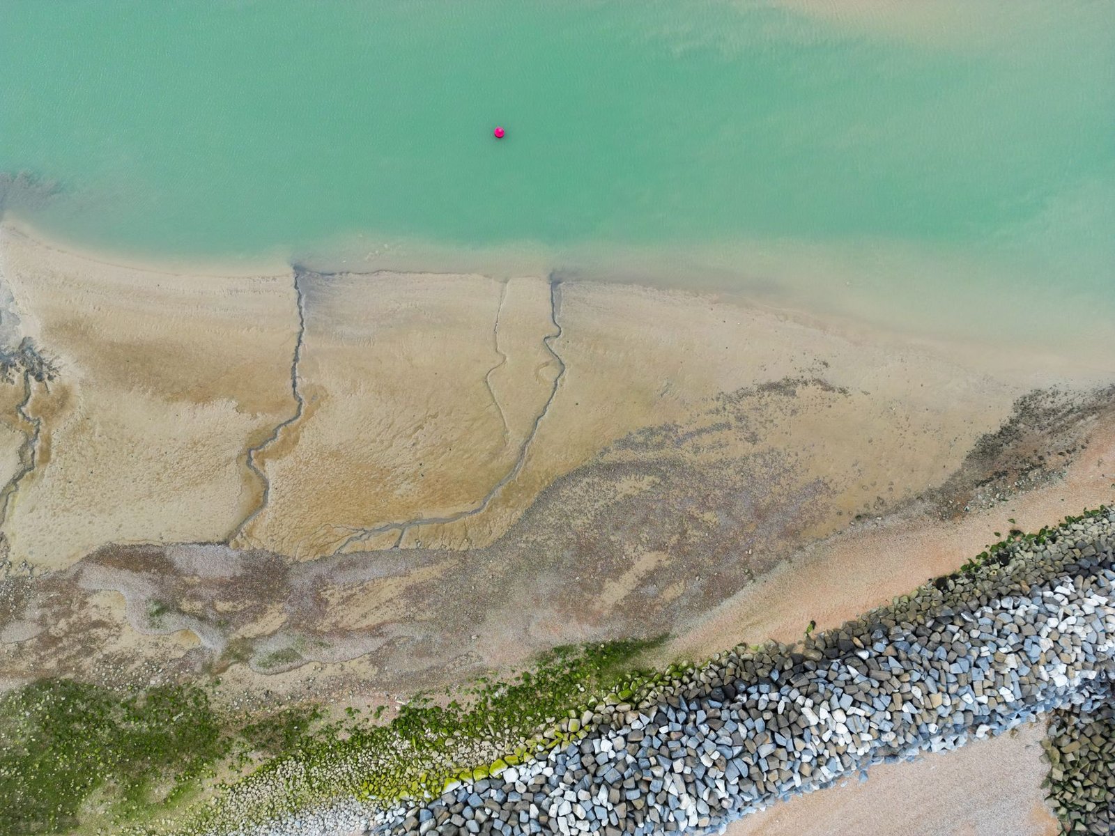 Aerial shot of the serene coastline at Eastbourne, England, featuring turquoise waters and sandy shores.