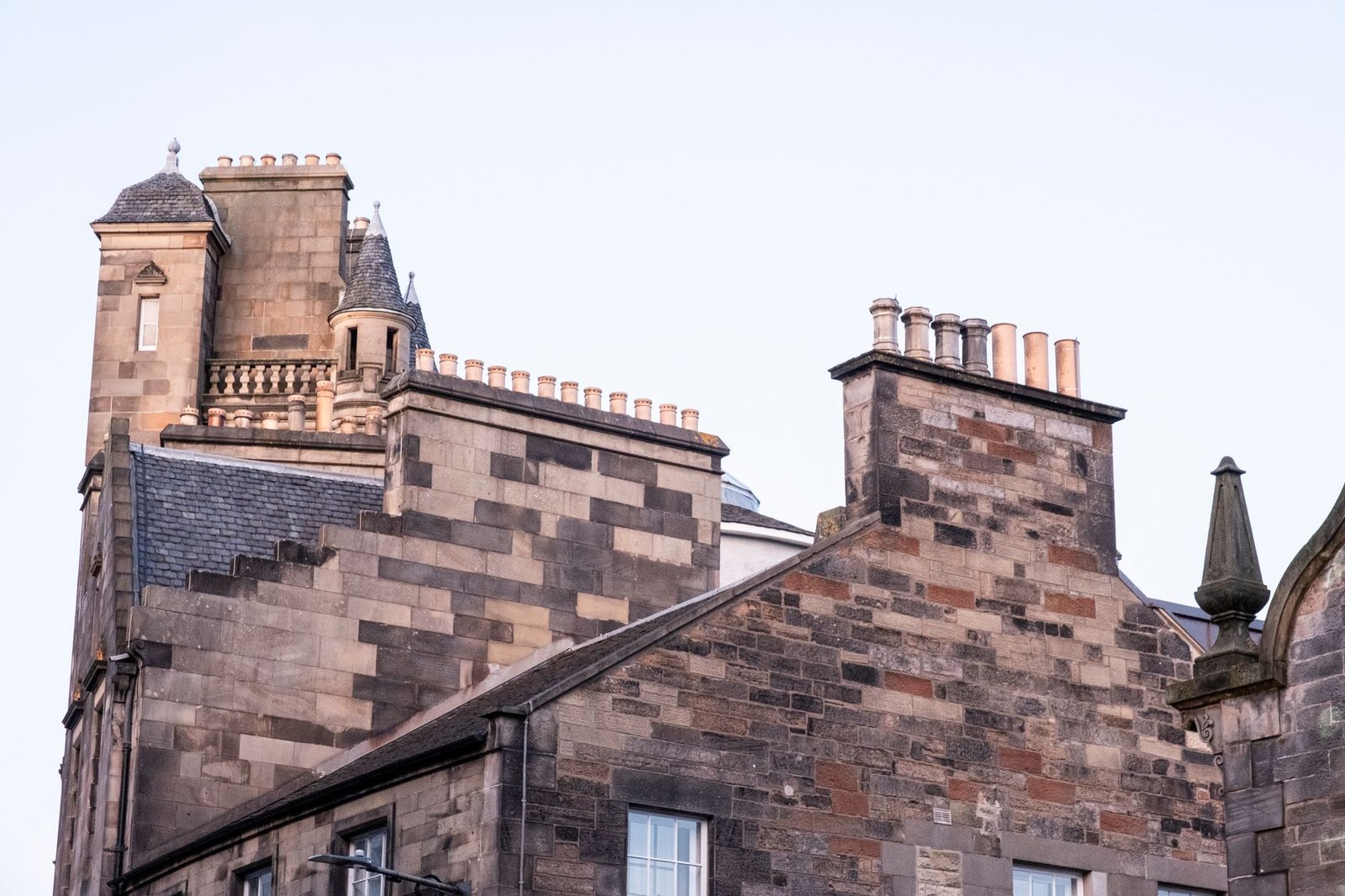 Close-up of Edinburgh's iconic stone architecture with chimneys at sunset.