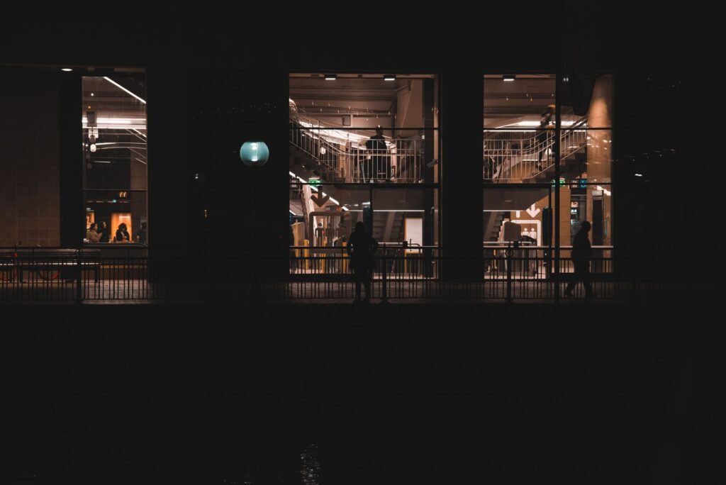 A modern building facade at night showcasing silhouettes and architectural lights.