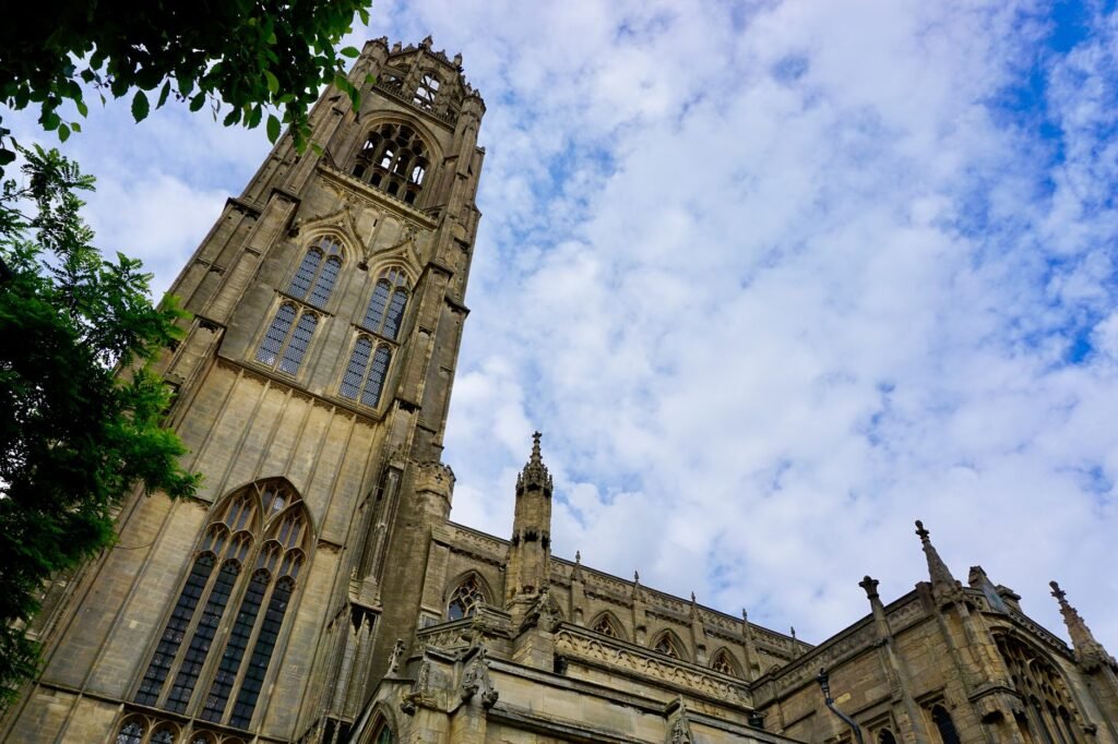 Low angle view of St Botolph's Church tower in Boston, England, under a cloudy blue sky.