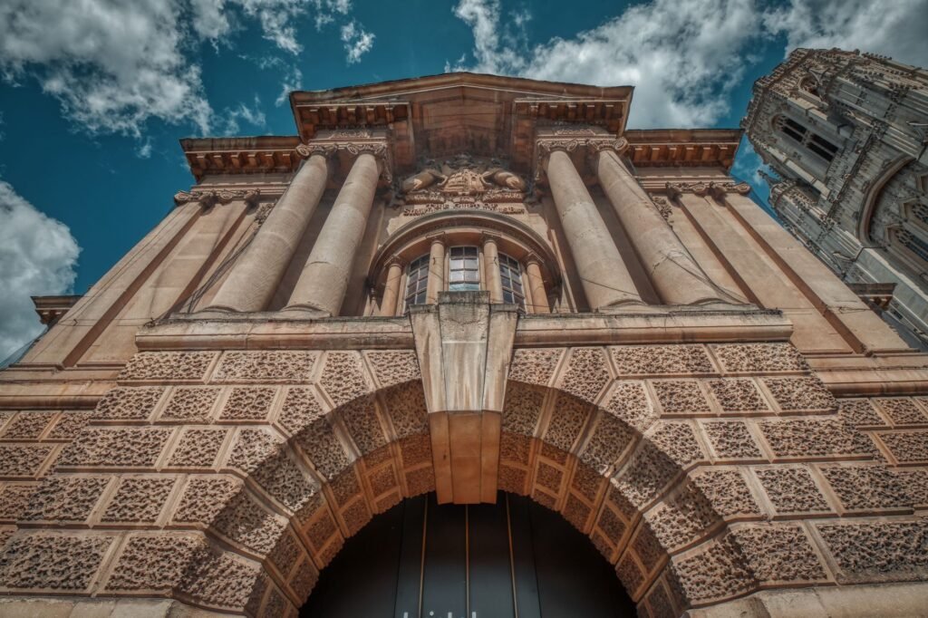 Low angle view of a historic building facade with columns in Bristol, England under a cloudy sky.
