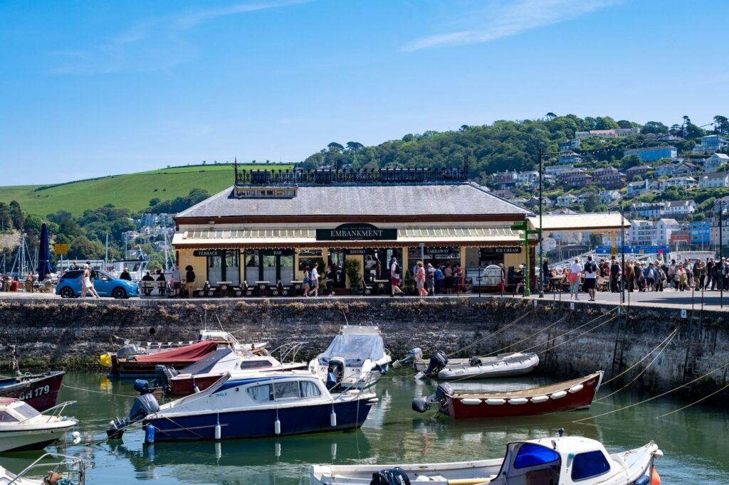 Lively scene of Dartmouth harbor with people and moored boats on a sunny day.