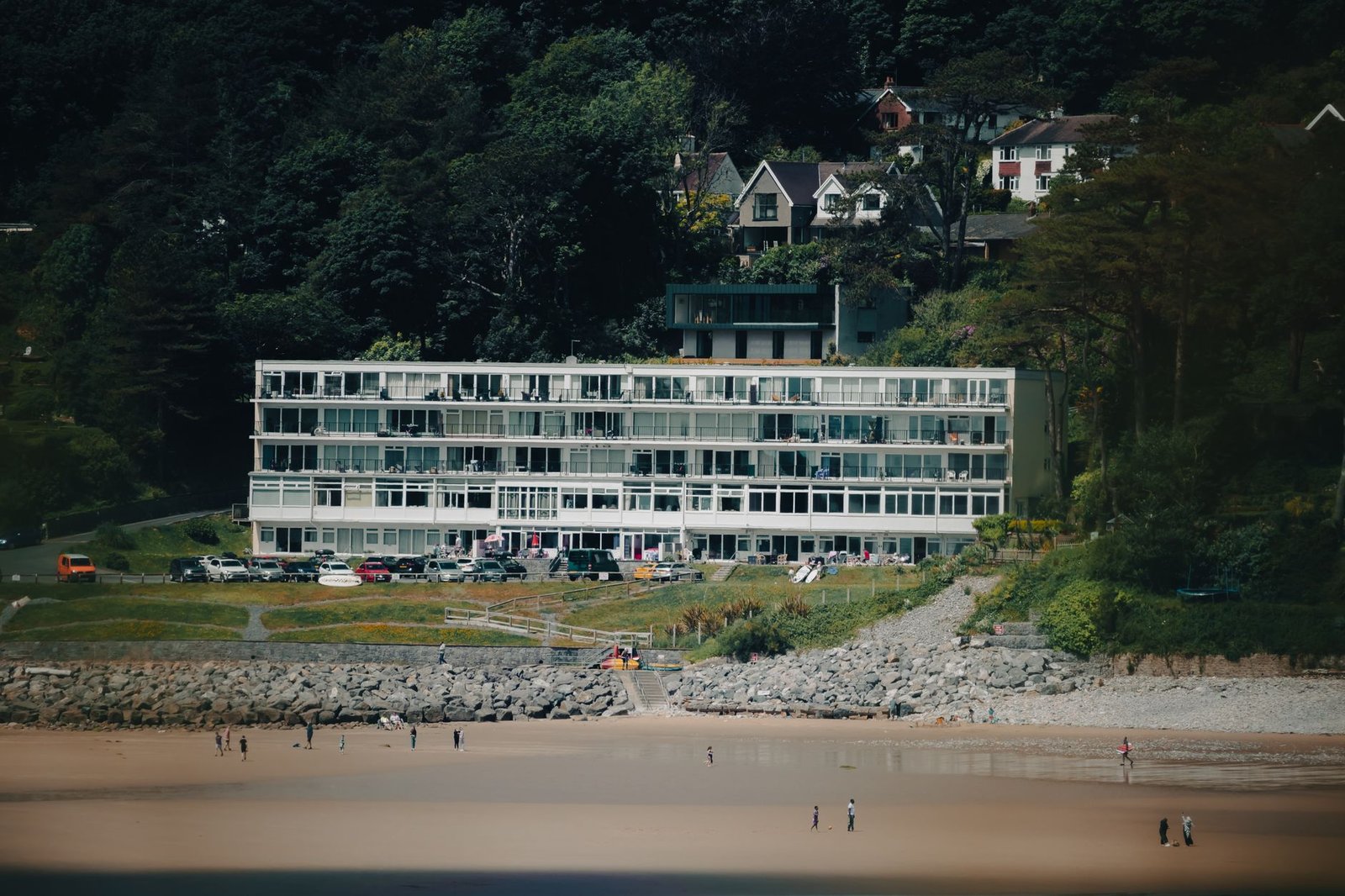 Scenic view of waterfront apartments at Caswell Bay, Wales with a sandy beach and lush greenery.