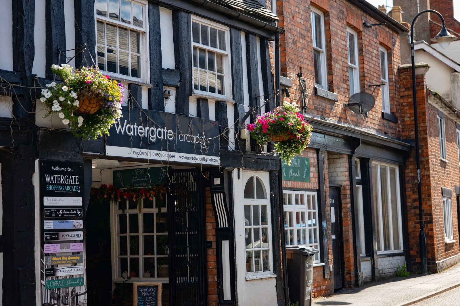 Charming Tudor architecture with flower baskets in Whitchurch, England, on a sunny day.