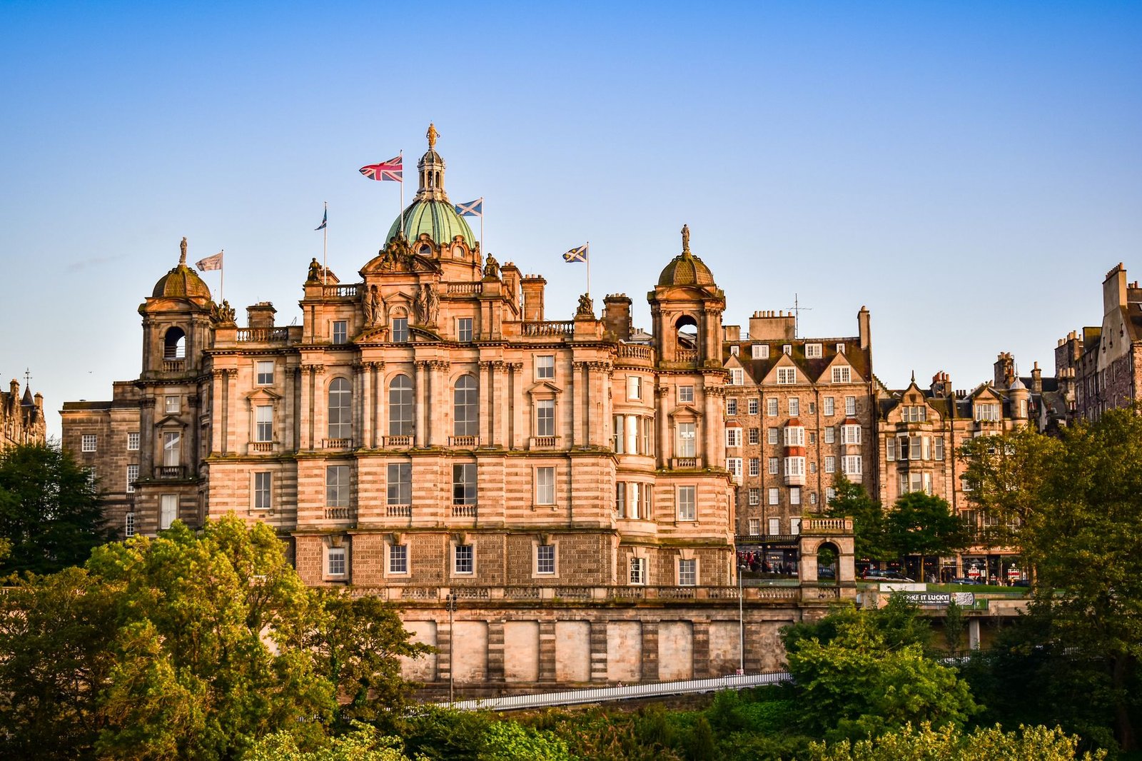 Picturesque view of an iconic building in Edinburgh with flags fluttering, captured at sunset.