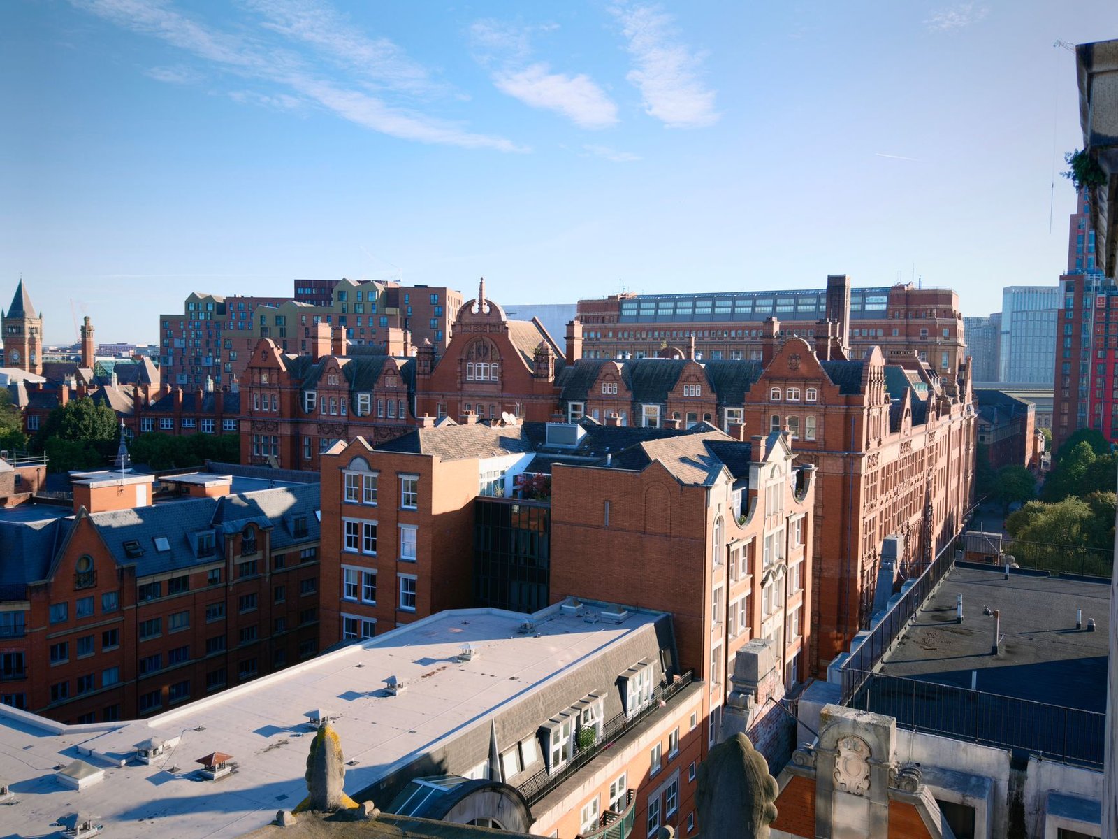 Stunning aerial view of red brick Victorian-style buildings in Manchester under a clear blue sky.
